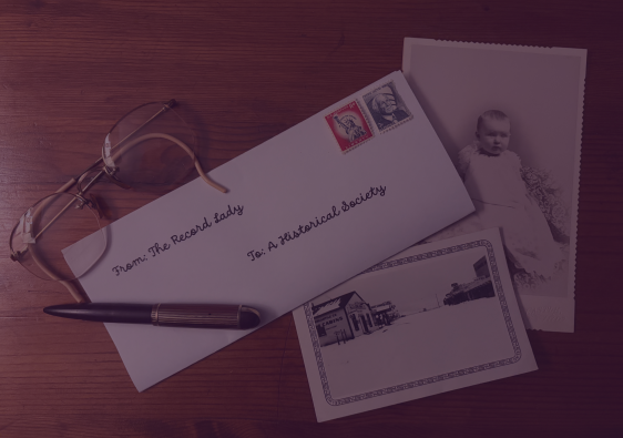 Letter addressed to a historical society on a desk with photographs.